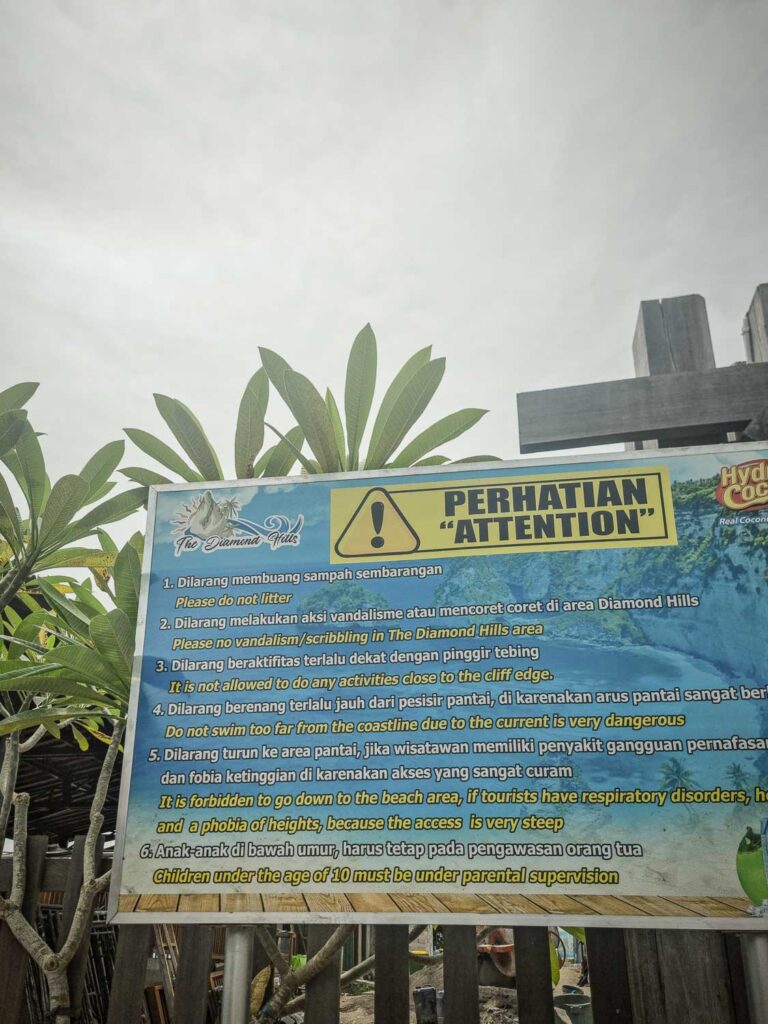 Information sign at Diamond Beach listing fines and safety precautions, including the no-swimming warning