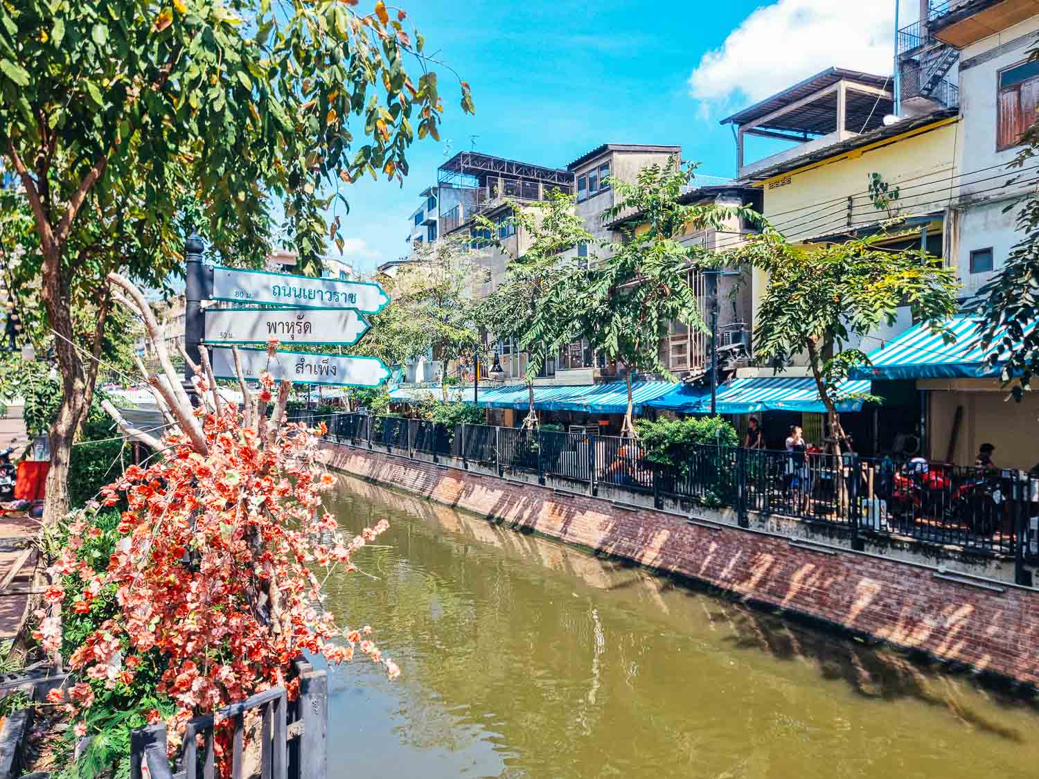 China Town Guide Bangkok Canals of Chinatown Grabbing a coffee by the river around Bangkok Chinatwon - Scenic Hua Met Canal in Bangkok with shops and outdoor seating.
