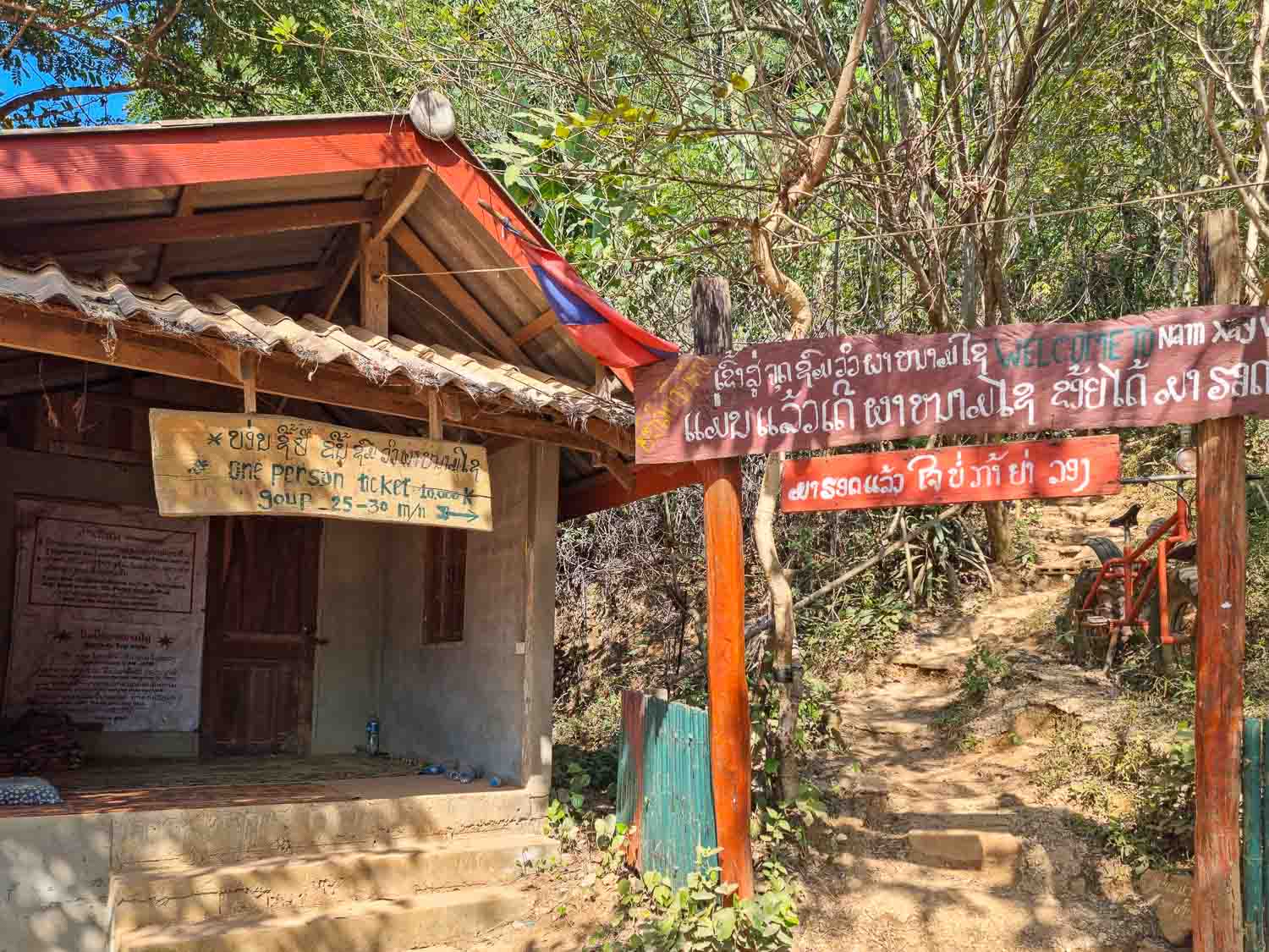Entrance and fee for Vang Vieng hike viewpoint Ticket Office/Entrance: The Nam Xay Viewpoint entrance and ticket office showing the 20,000 LAK fee sign and jungle path.