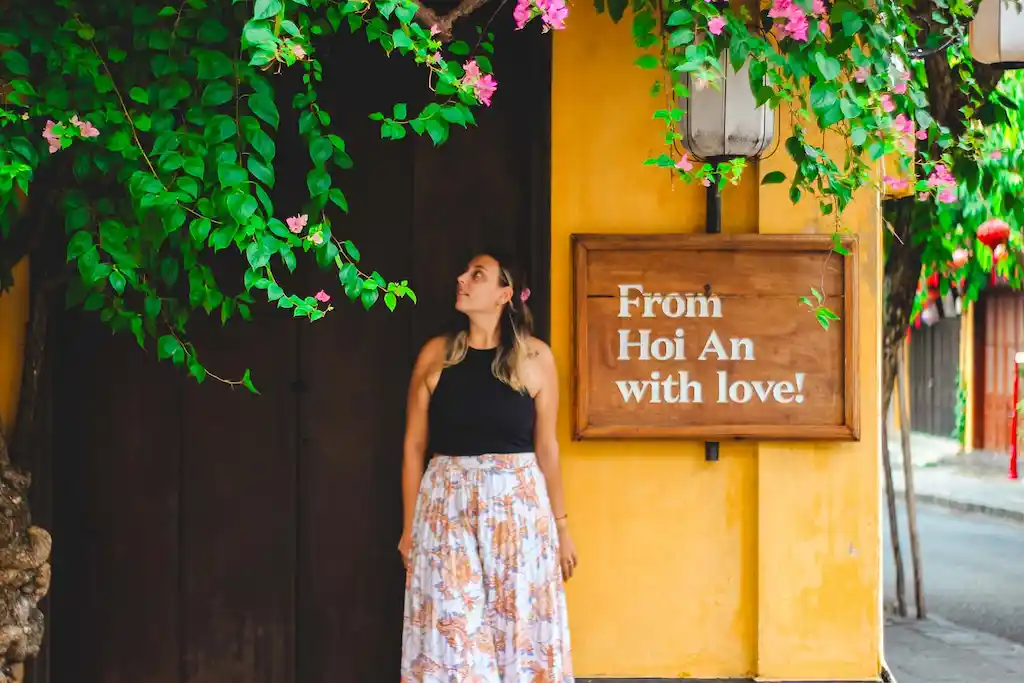 The famous sign of Hoi An - Ale standing nearby the love hoi an sign - mustard yellow wall and pinky flowers