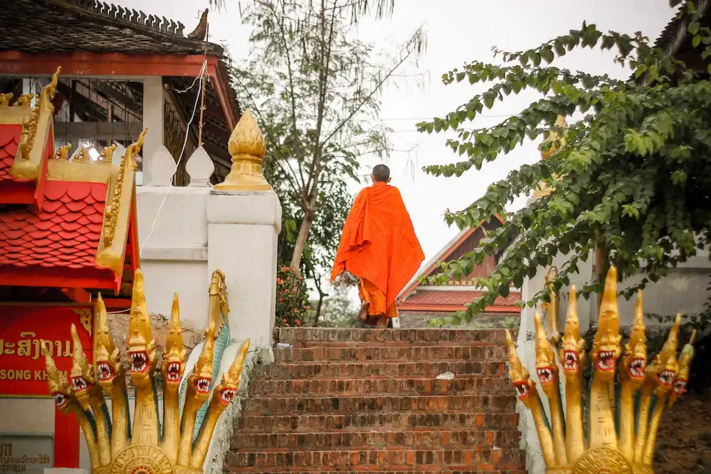Luang Prabang itinerary | A mong entering the monastery in Luang Prabang in his saffron robe