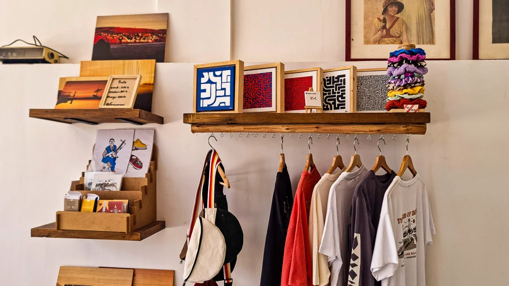 Tamraght Digital Nomads Guide - The merchandising shop at our favourite coffee shop in Tamraght Surf and Friends with postcards, shirts, bumbags and old photos of travellers to Morocco Atlantic Coast.
