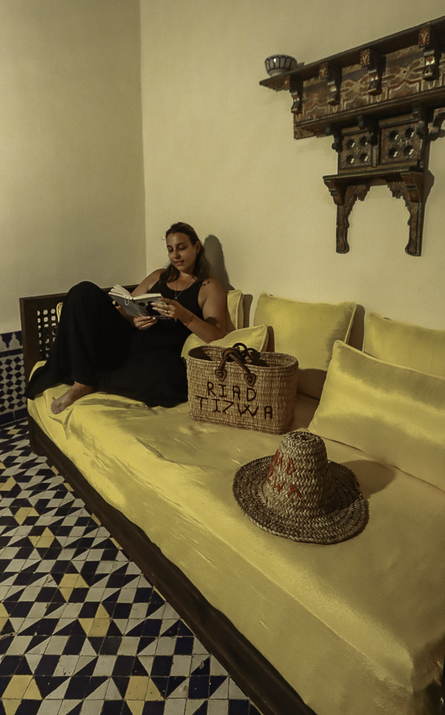 Ale reading a book on the sofa of our room at Riad Tizwa Fes
