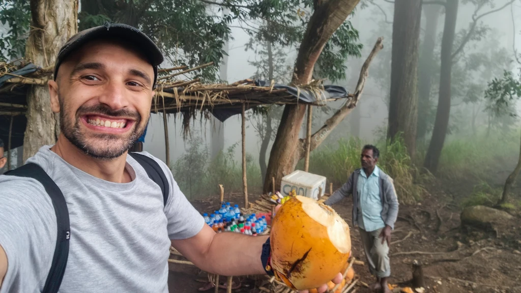 Grabbing a coconut on the way down from Ella rock Getting a fresh coconut on top of Ella Rock from a local vendor that carry it for 300 metres vertical to the top every morning